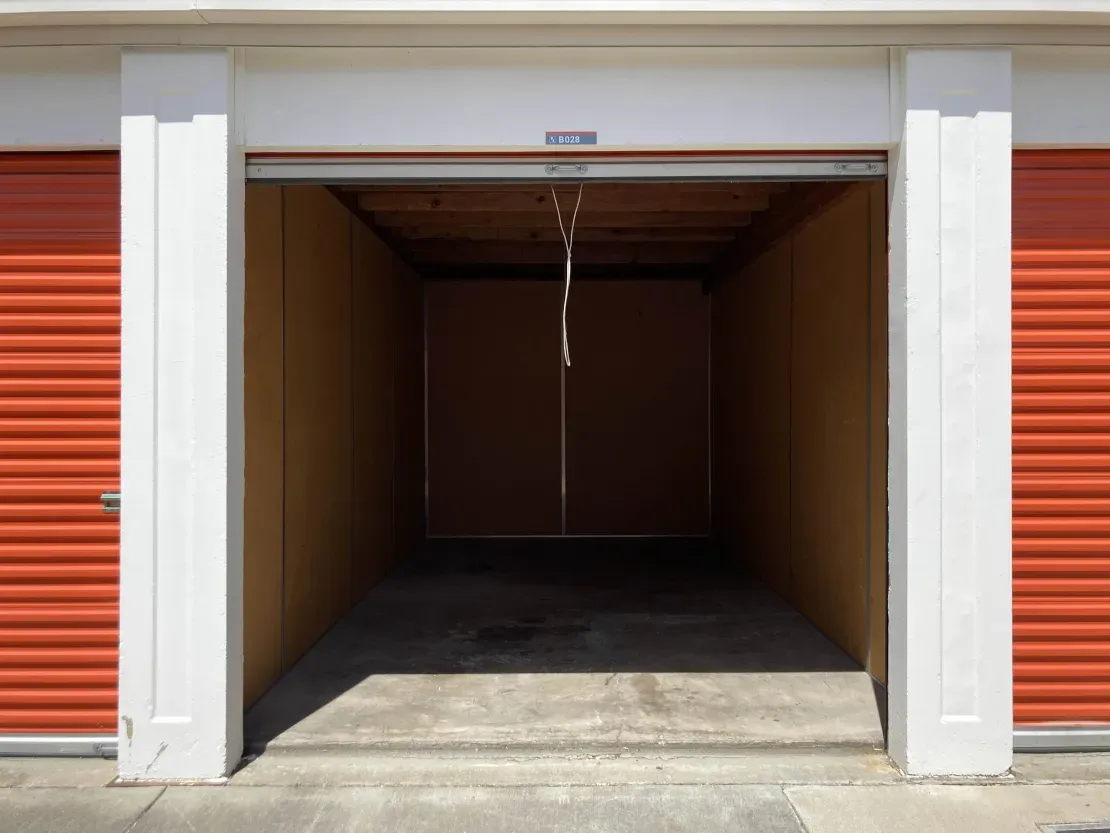 An empty drive-up storage unit with its roll-up door open